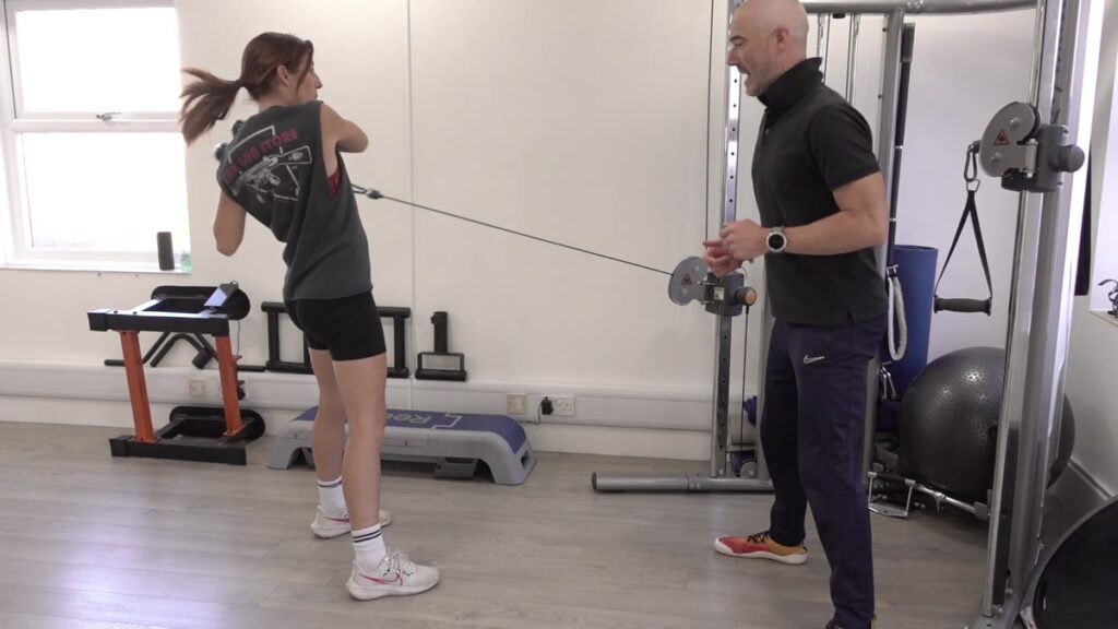 Dom Meacher coaching a client through a rotating cable pull at Ocean Fitness Poole