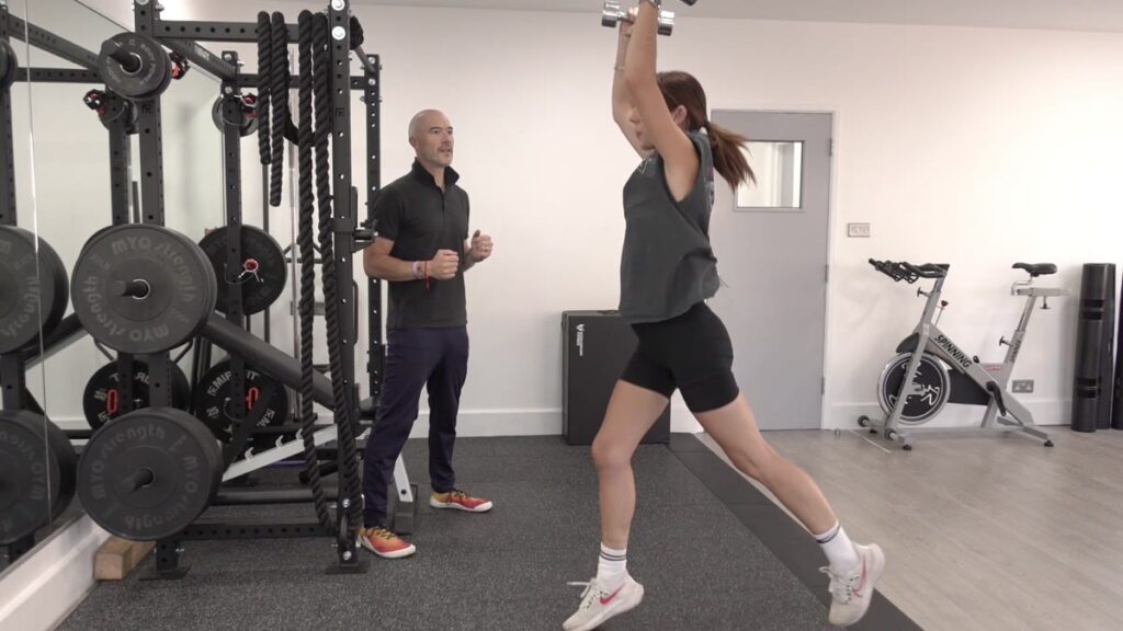 Dom Meacher coaching a client through a lunge and overhead press at Ocean Fitness Poole